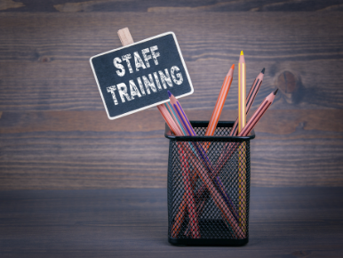 A small staff training sign in a pencil holder with colorful pencils.