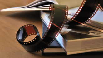 Picture of 2 books stacked upon each other with a roll of film on top