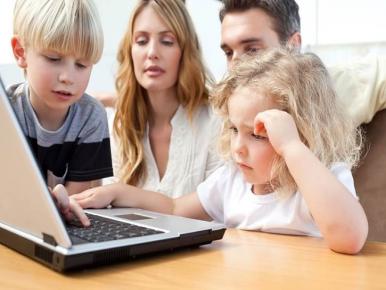 family with small children working on a laptop