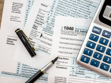 IRS tax forms laid out on a table with a pen and calculator on top of them