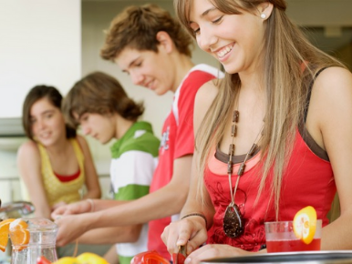 Four teens cutting up food and smiling