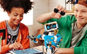 Two teenagers smiling and playing with an iPad and a robot