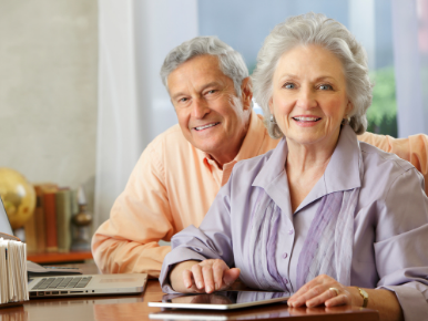 Senior Citizen man and woman sitting together at a table smiling