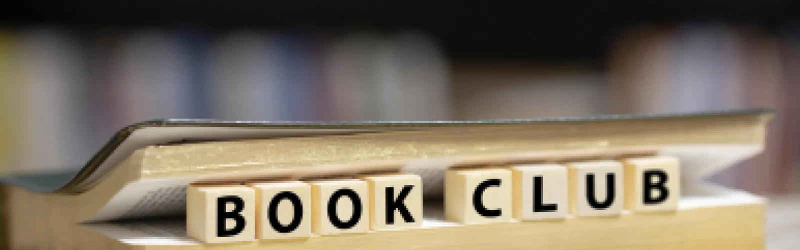 The letters "Book Club" on titles laid out in between book pages.